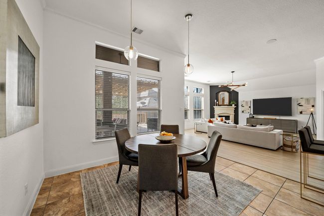 Open breakfast area near the kitchen offers a casual dining space with tile flooring. Natural light floods through oversized windows, while pendant lighting fixtures illuminate the space. | Image 22