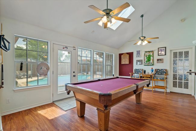 Game room with a ceiling fan, wood finished floors, billiards, high vaulted ceiling, and baseboards | Image 11