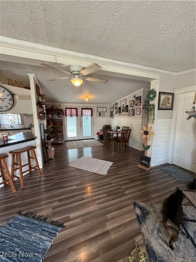 Living area with ceiling fan, ornamental molding, wood finished floors, and a textured ceiling | Image 6