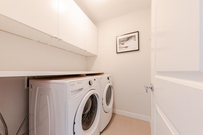 Laundry area featuring independent washer and dryer, cabinet space, and light tile patterned flooring | Image 20