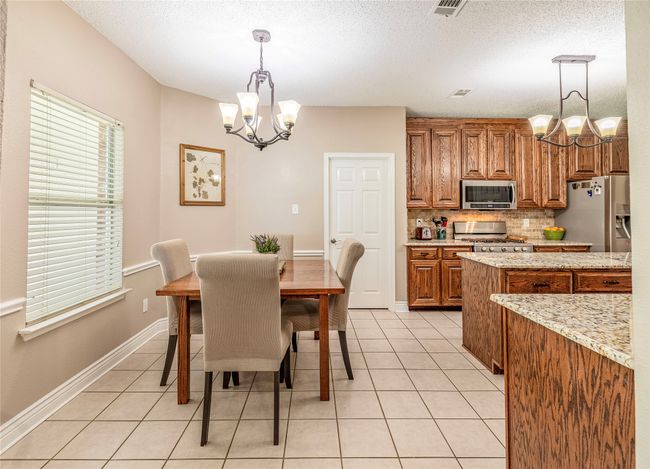 Dining room with a chandelier, light tile patterned flooring, a textured ceiling, and baseboards | Image 16