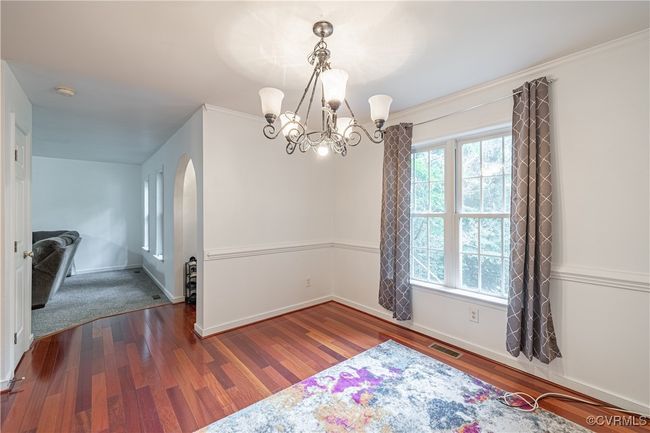 Unfurnished dining area with a chandelier, wood finished floors, arched walkways, and ornamental molding | Image 5