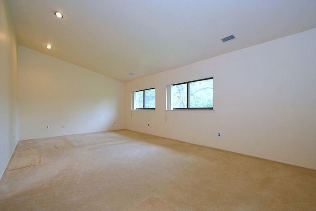 Empty room featuring vaulted ceiling, light colored carpet, visible vents, and recessed lighting | Image 12
