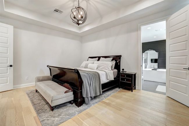 Primary bedroom with light wood floors, a tray ceiling | Image 14