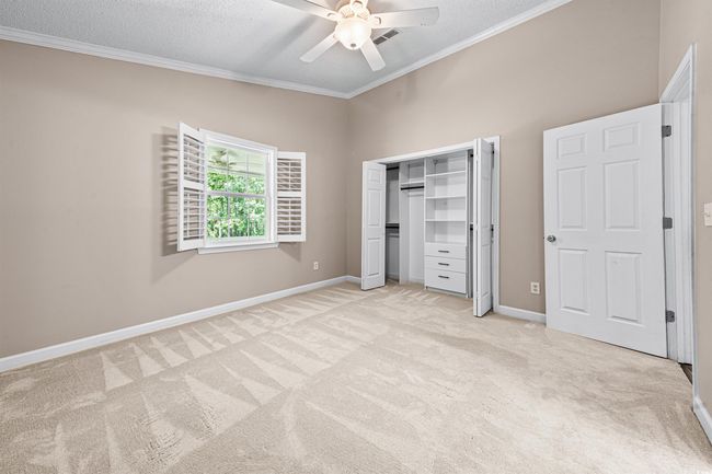 Unfurnished bedroom featuring baseboards, ornamental molding, a ceiling fan, and light carpet | Image 18
