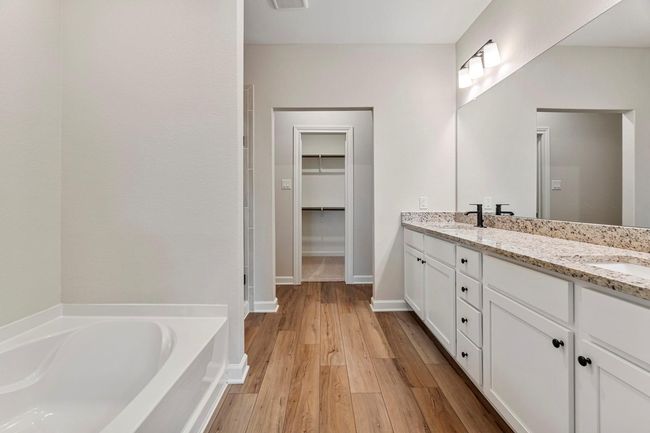 Welcome to the en-suite bathroom, where a sleek granite vanity and mirror provide a stylish focal point, and a separate tub and shower combo offer the ultimate in comfort and convenience. With its thoughtfully designed layout and luxurious amenities, this private retreat is the epitome of modern luxury | Image 9