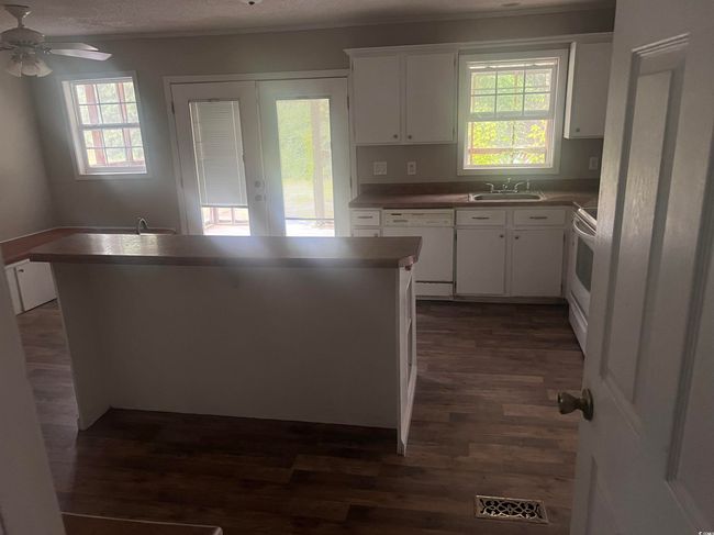 Kitchen featuring white appliances, dark wood-style floors, a sink, white cabinetry, and a ceiling fan | Image 6