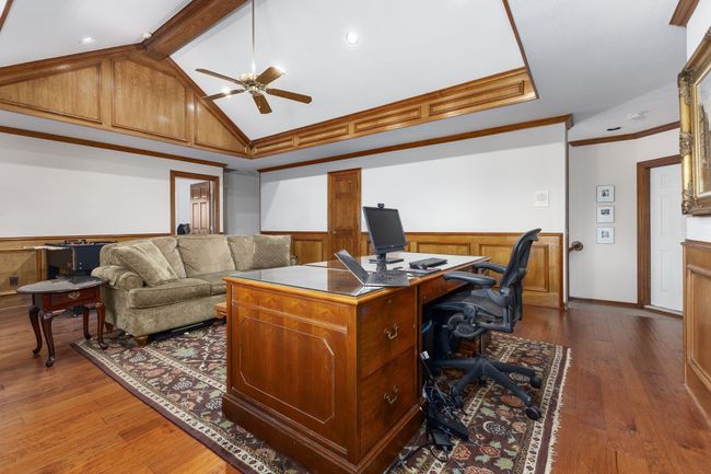 Office area featuring ceiling fan, vaulted ceiling with beams, a wainscoted wall, wood-style floors, and crown molding | Image 15