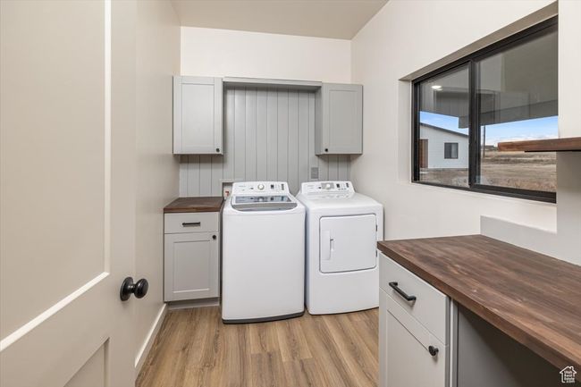Clothes washing area featuring cabinets, light hardwood / wood-style floors, and washer and clothes dryer | Image 31