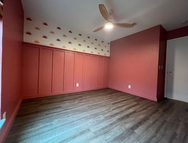 Unfurnished room featuring wainscoting, wallpapered walls, dark wood-style floors, and ceiling fan | Image 33