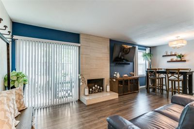 Living room featuring a large fireplace, dark hardwood / wood-style floors, and a healthy amount of sunlight | Image 1