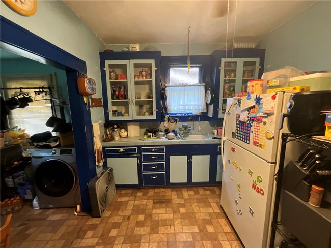 Kitchen featuring tile countertops, washer / dryer, glass insert cabinets, and freestanding refrigerator | Image 5