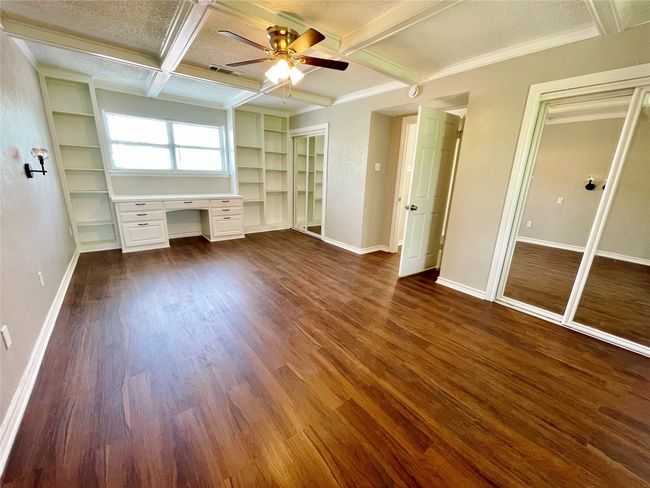 Unfurnished bedroom featuring dark wood finished floors, built in study area, coffered ceiling, beamed ceiling, and baseboards | Image 17