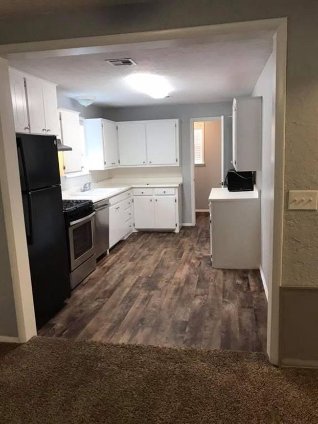 Kitchen with dark wood finished floors, stainless steel appliances, light countertops, visible vents, and white cabinetry | Image 7