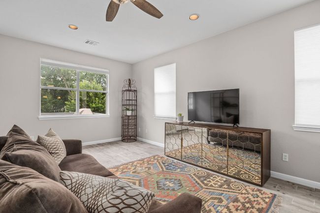 Living area featuring wood finished floors, visible vents, a healthy amount of sunlight, and baseboards | Image 11
