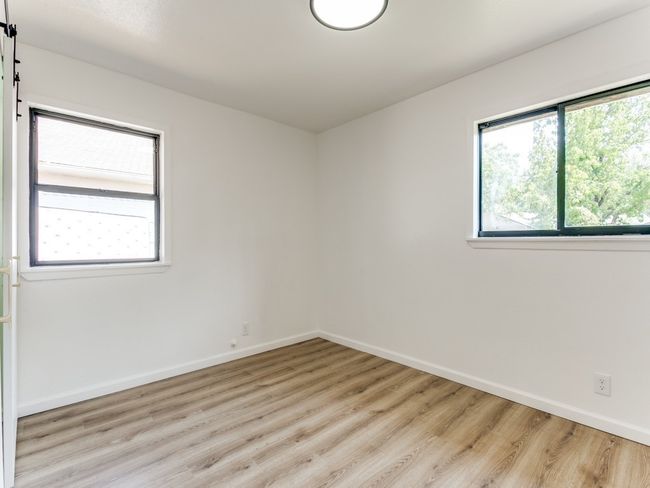 Spare room with a barn door, baseboards, and light wood-style flooring | Image 4