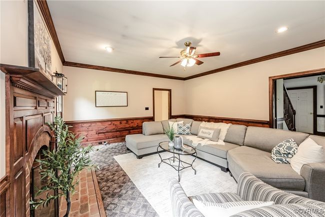 Living room with a wainscoted wall, ceiling fan, ornamental molding, carpet flooring, and a fireplace | Image 14