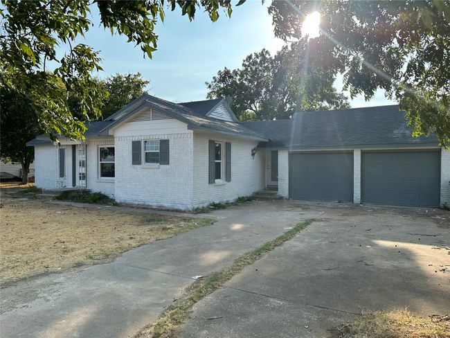 Ranch-style house with concrete driveway, brick siding, and a garage | Image 38
