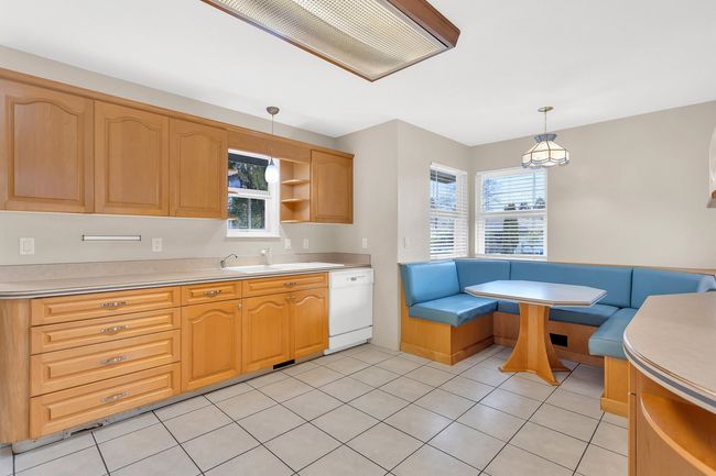 Kitchen featuring open shelves, breakfast area, a sink, pendant lighting, and dishwasher | Image 7