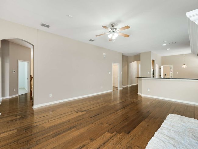 Unfurnished living room featuring arched walkways, a ceiling fan, dark wood finished floors, and recessed lighting | Image 11