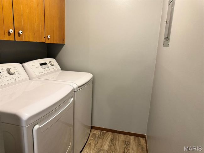 Laundry room with cabinet space, independent washer and dryer, and wood finished floors | Image 20