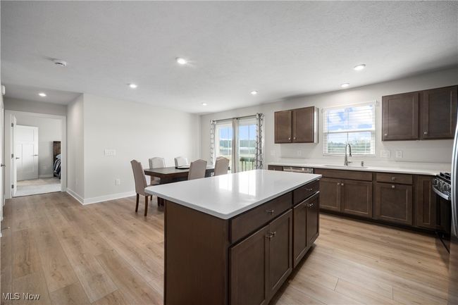 Kitchen featuring dark brown cabinetry, light wood-style flooring, light countertops, and a sink | Image 16