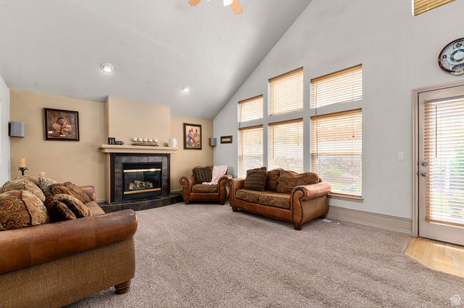 Living area with carpet flooring, healthy amount of natural light, a fireplace, and high vaulted ceiling | Image 11