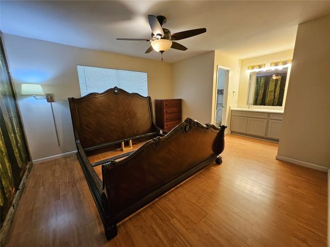 Bedroom featuring light wood-style floors, connected bathroom, and a ceiling fan | Image 12