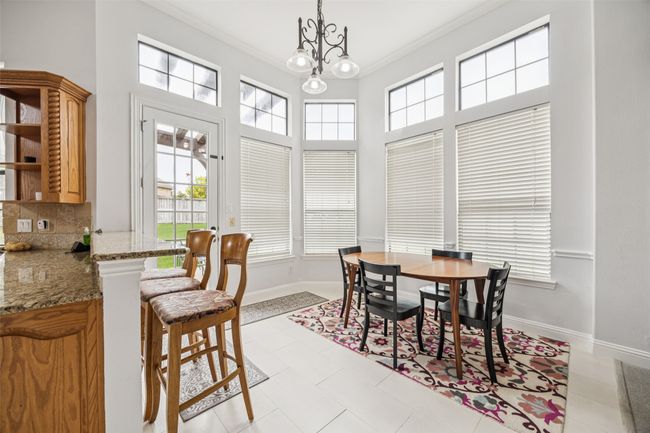 Dining room with healthy amount of natural light, crown molding, a chandelier, light tile patterned floors, and a towering ceiling | Image 9