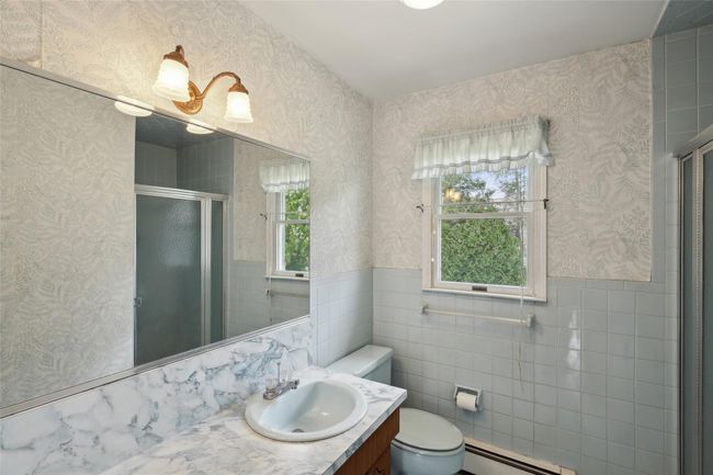 Bathroom featuring a shower stall, a baseboard radiator, vanity, a wainscoted wall, and toilet | Image 25