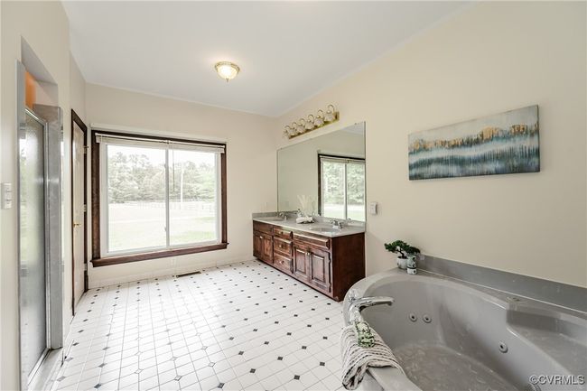 Bathroom featuring a tub with jets, double vanity, a shower stall, and tile patterned floors | Image 21