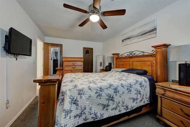 Bedroom featuring baseboards, dark carpet, a ceiling fan, and a textured ceiling | Image 8