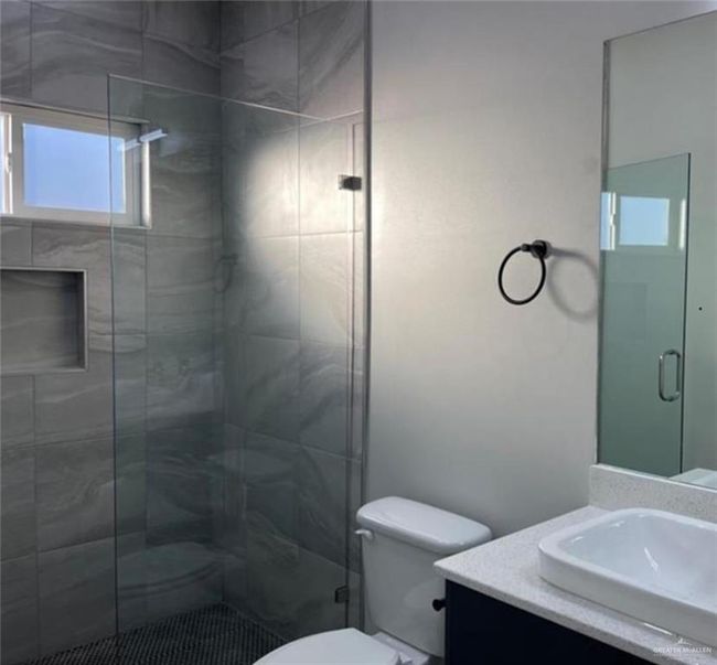 Bathroom with vanity, toilet, and a shower with door | Image 9