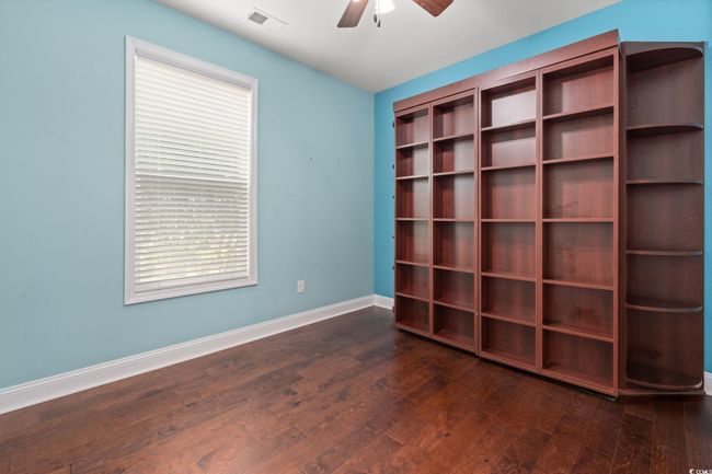 Empty room with dark wood-type flooring, visible vents, a ceiling fan, and baseboards | Image 25