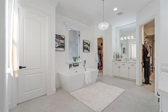 His and hers closets with generous storage space and built-in shelves, adding to the home’s luxury features. Neutral finishes throughout the bathroom and closets create a timeless, tranquil ambiance. | Image 23