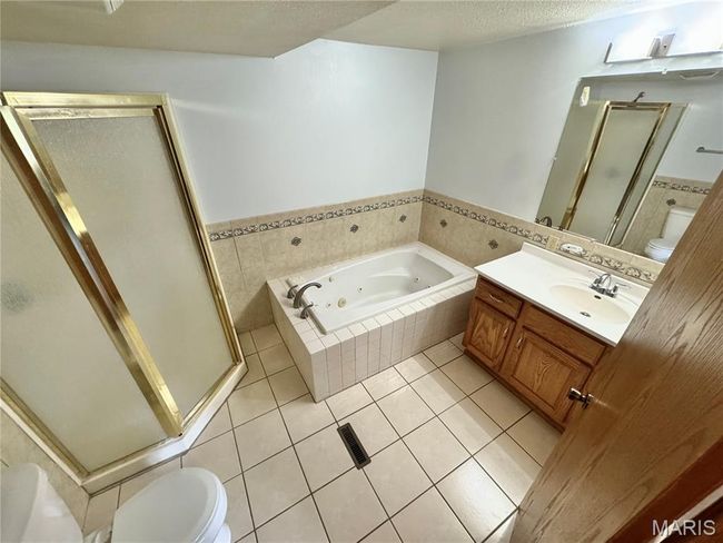 Full bath featuring toilet, a whirlpool tub, a stall shower, vanity, and a textured ceiling | Image 16