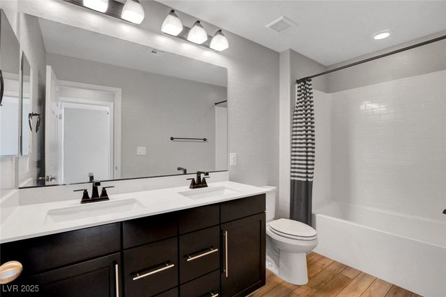 Bathroom featuring wood finished floors, shower / tub combo, toilet, and double vanity | Image 38