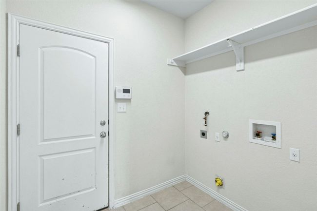 Washroom featuring hookup for a gas dryer, electric dryer hookup, baseboards, hookup for a washing machine, and light tile patterned floors | Image 19