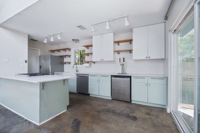Kitchen with open shelves, appliances with stainless steel finishes, and tasteful backsplash | Image 6