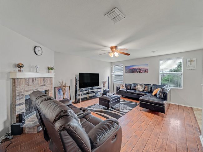Living area featuring ceiling fan, hardwood / wood-style flooring, a fireplace, and baseboards | Image 4