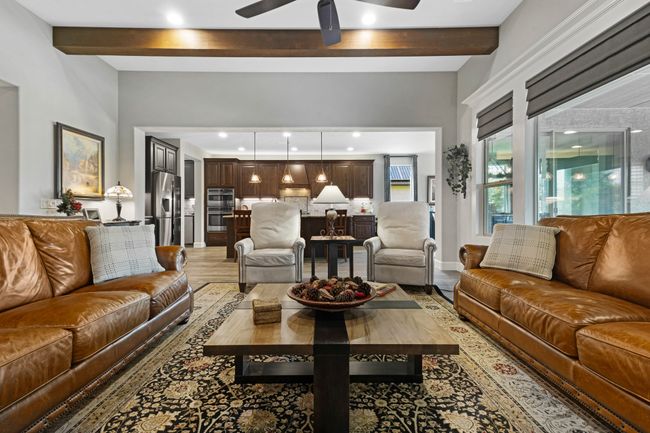 Living room with light wood finished floors, beam ceiling, a ceiling fan, and recessed lighting | Image 8