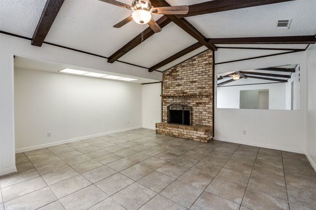 Unfurnished living room featuring ceiling fan, a textured ceiling, tile patterned floors, and a fireplace | Image 5