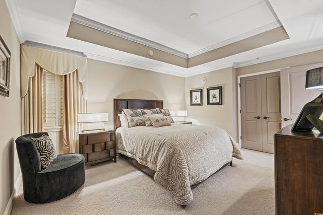 Bedroom with light colored carpet, a tray ceiling, ornamental molding, and a closet | Image 25