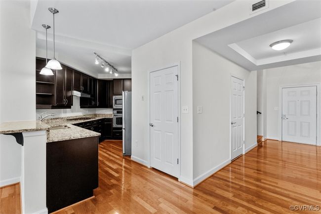 Kitchen with a sink, light wood-type flooring, visible vents, open shelves, and light stone countertops | Image 12