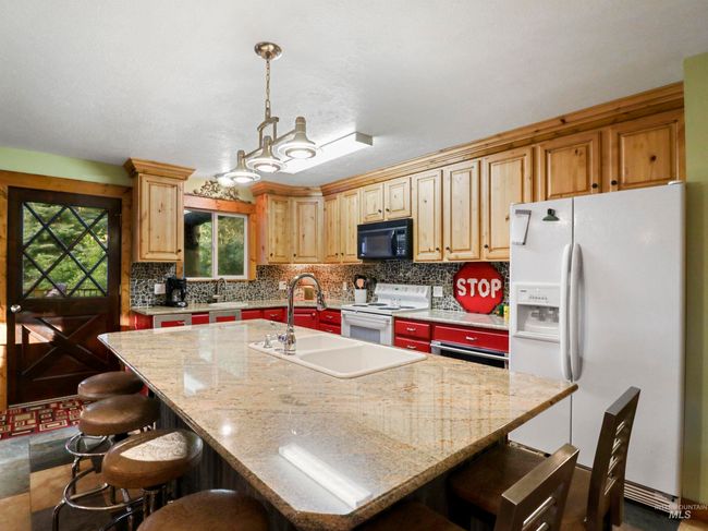Kitchen with white appliances, tasteful backsplash, a kitchen island with sink, and a breakfast bar area | Image 27