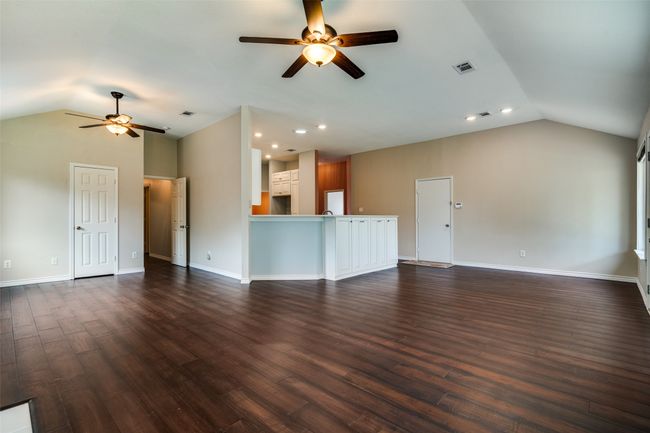 Unfurnished living room with vaulted ceiling, ceiling fan, dark wood finished floors, and recessed lighting | Image 11