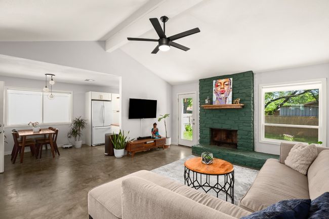 Living room with finished concrete flooring, healthy amount of natural light, ceiling fan, and a stone fireplace | Image 4