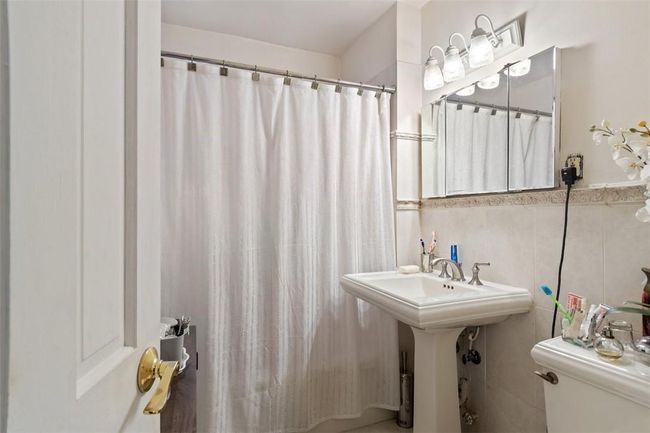Bathroom with tasteful backsplash, tile walls, toilet, and sink | Image 14