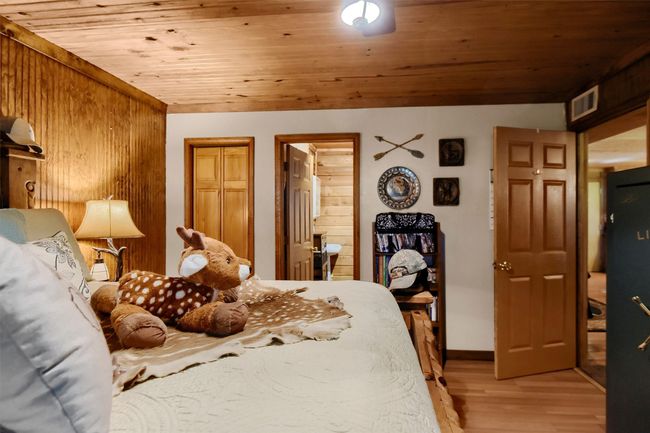 Bedroom with light wood-style flooring, wooden ceiling, baseboards, and visible vents | Image 23