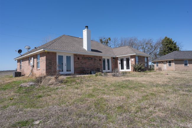 Back of house featuring french doors, brick siding, a chimney, central AC unit, and a lawn | Image 24